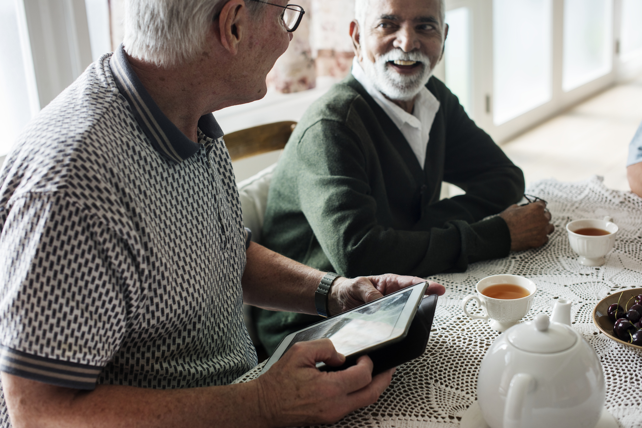 Two men sitting together on a table talking 