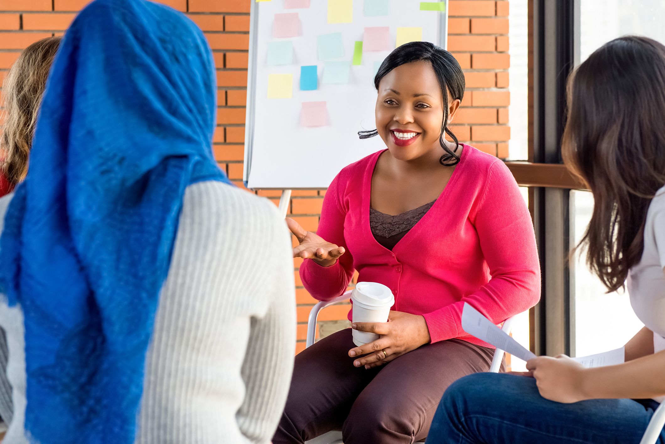 People sitting together discussing with a white board behind