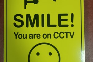 Yellow sign with big smiley face saying smile you're on CCTV