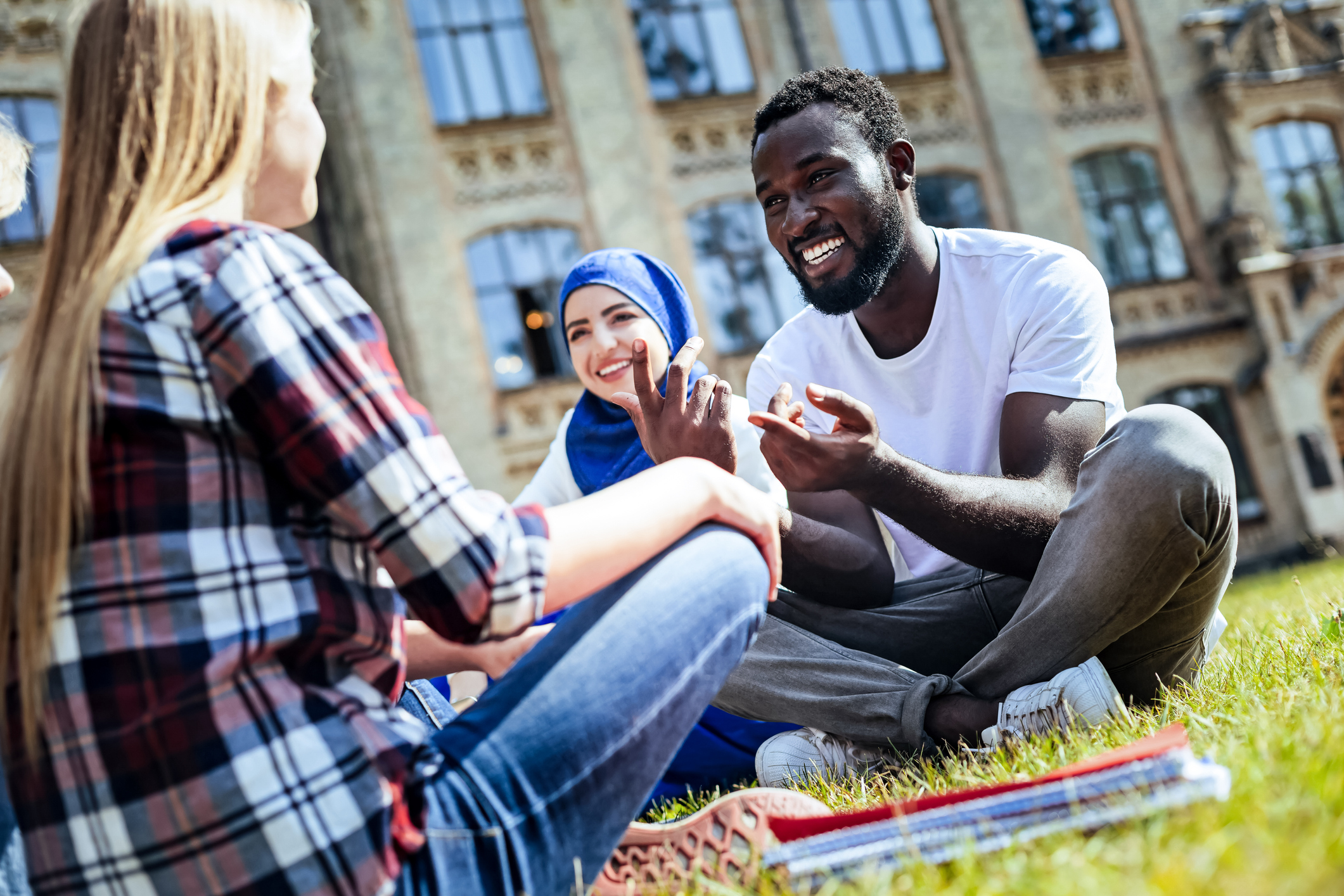 Adults sitting on grass laughing and talking happily 